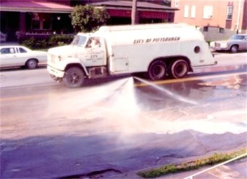 Photo of city cleaning truck spraying down Brookline
 Boulevard.